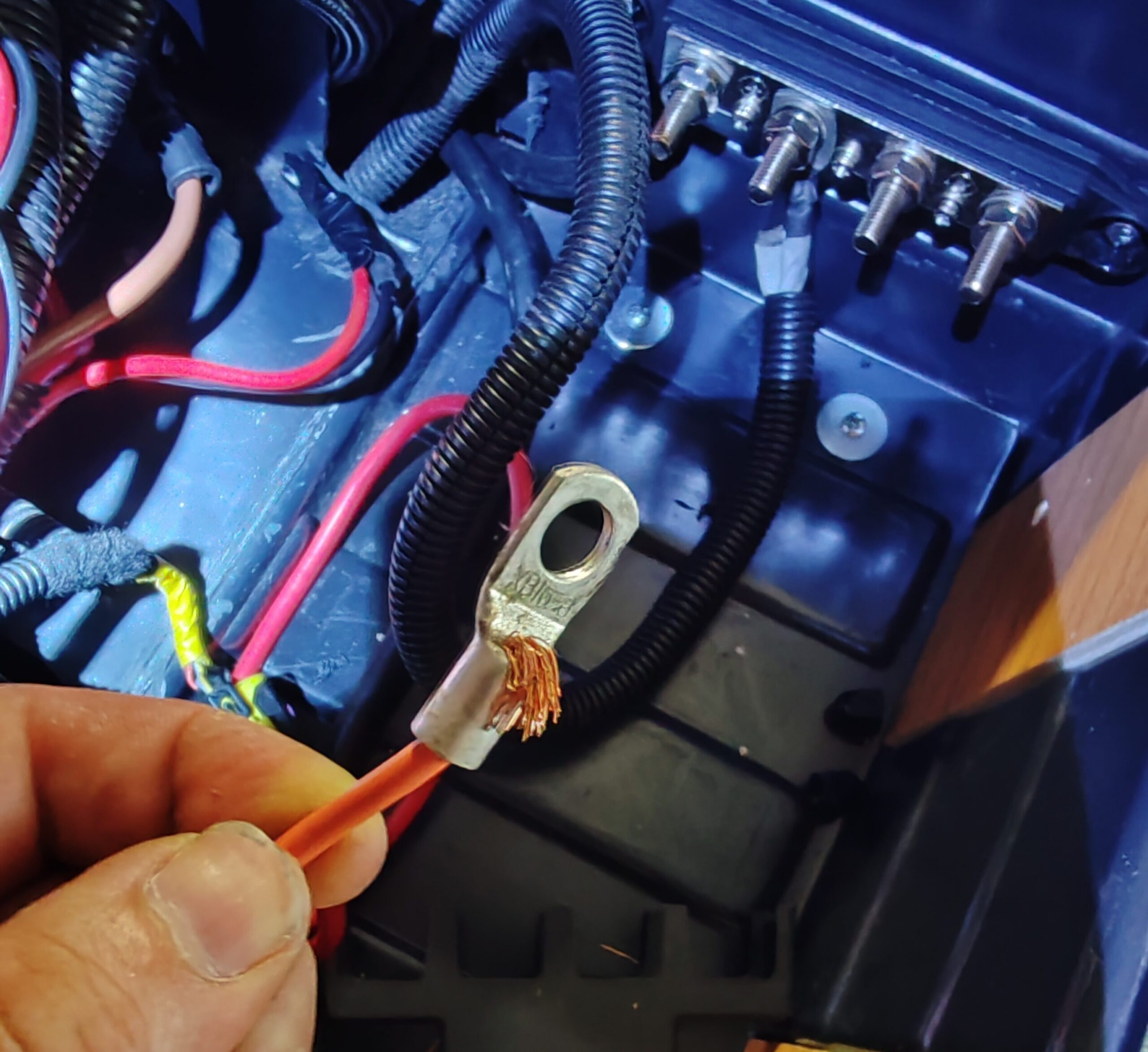 Cable eléctrico con los hilos atravesando un terminal de ojal demasiado grande y sin un crimpado correcto.