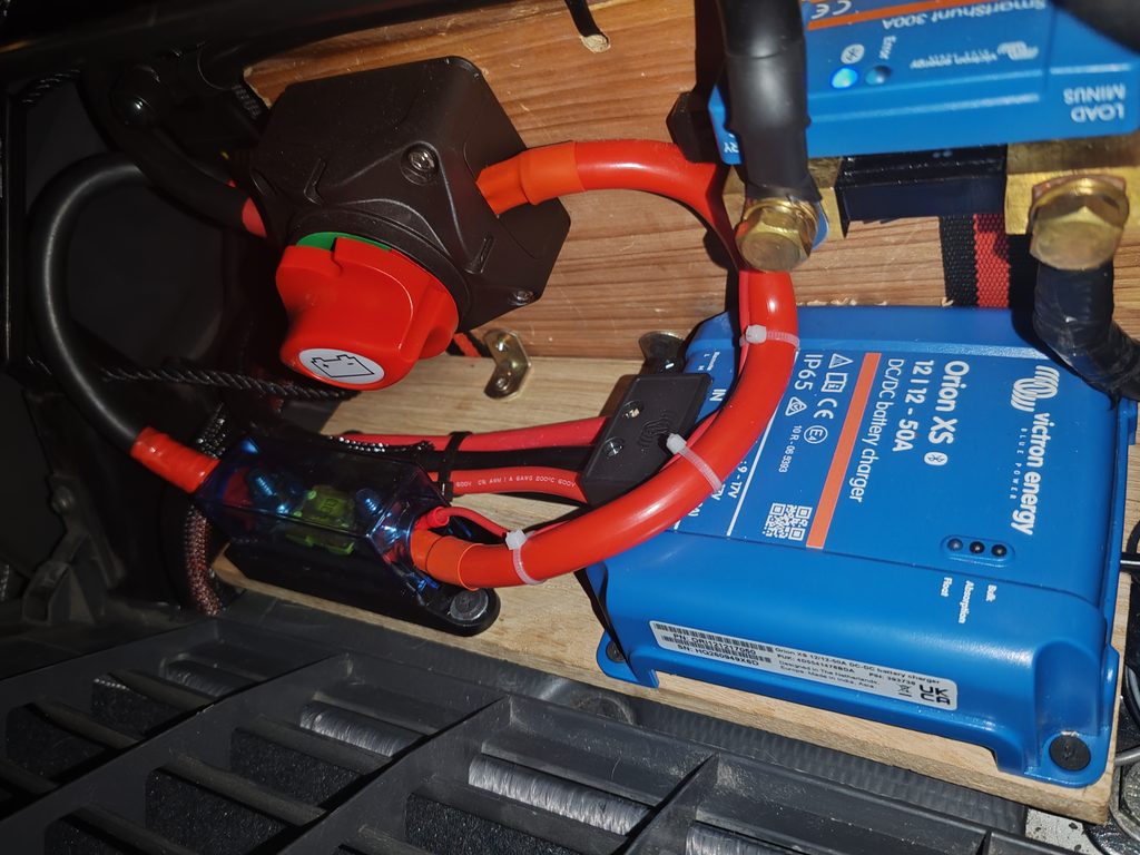 Instalación eléctrica bajo el asiento con Victron Orion XS, seccionador, fusible principal y conexiones de la batería LiFePO₄.
